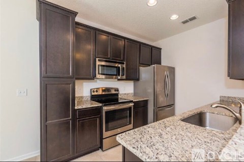 A kitchen with dark brown cabinets and stainless steel appliances.