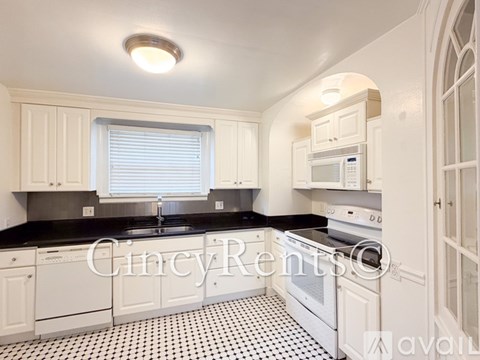 A kitchen with black and white tiled flooring and white cabinets.