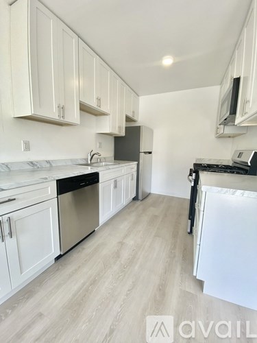 A kitchen with white cabinets and a white fridge.