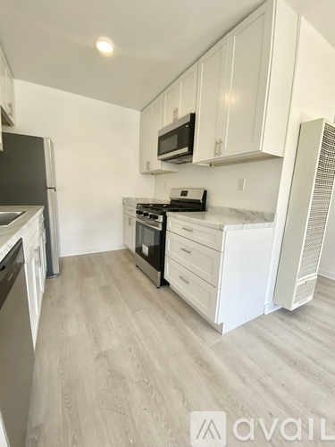 A kitchen with white cabinets and a wooden floor.
