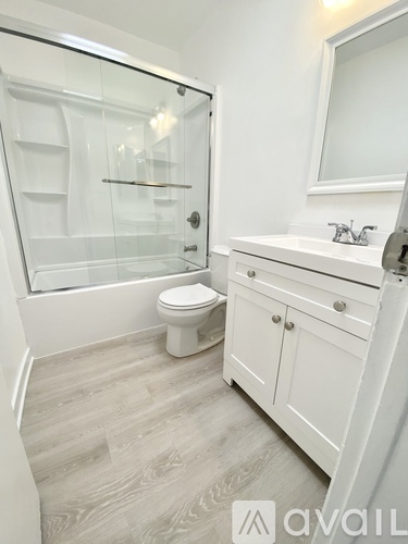 A white bathroom with a glass shower stall and a toilet.