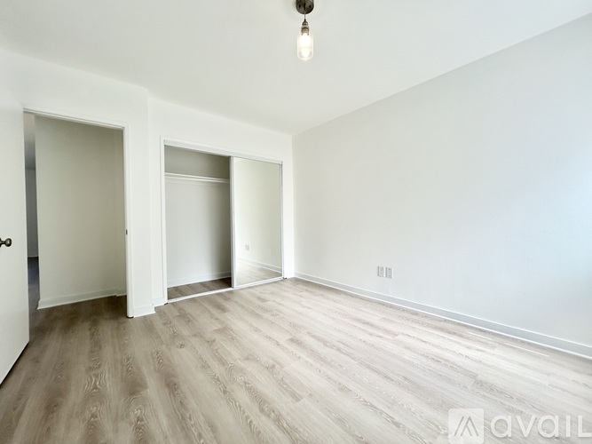 A spacious room with wooden flooring and white walls.
