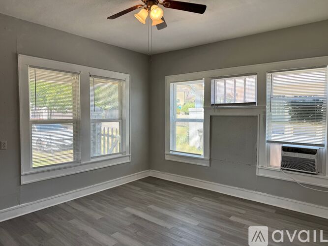 A room with a ceiling fan and two windows.