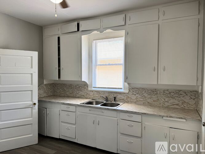 A kitchen with white cabinets and a marble countertop.