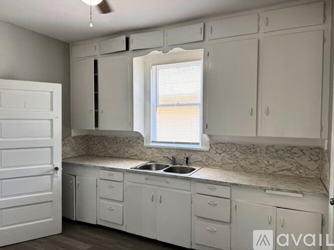 A kitchen with white cabinets and a marble countertop.