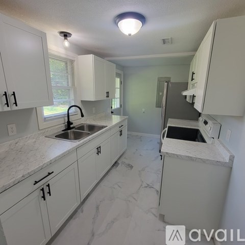 A kitchen with white cabinets and marble countertops.