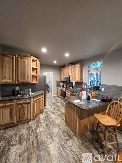 A kitchen with wooden cabinets and a countertop with a chair.
