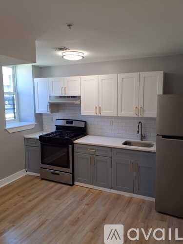 A kitchen with wooden floors and a refrigerator on the right side.