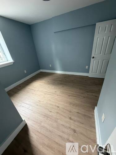 A room with wooden flooring and a white door.