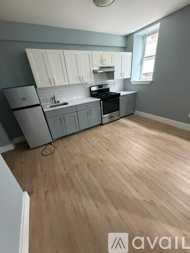 A kitchen with wooden floors and grey cabinets.