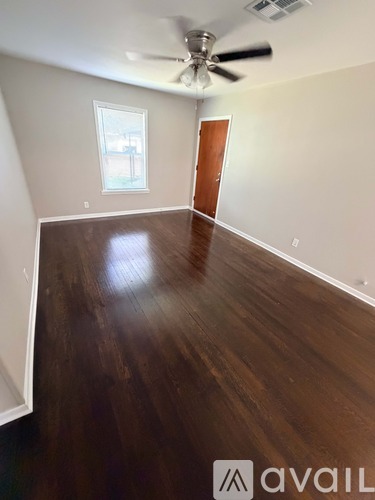 A room with a ceiling fan and wooden flooring.