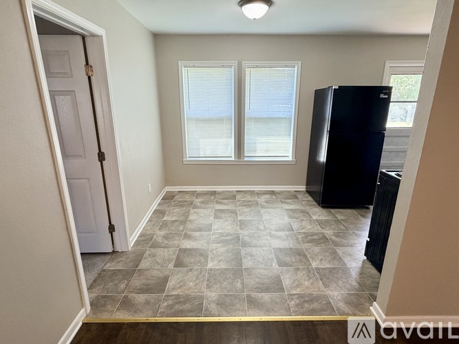A kitchen area with a black refrigerator and a tiled floor.