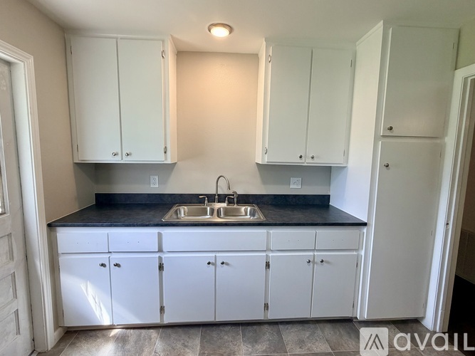 A kitchen with white cabinets and a black countertop.