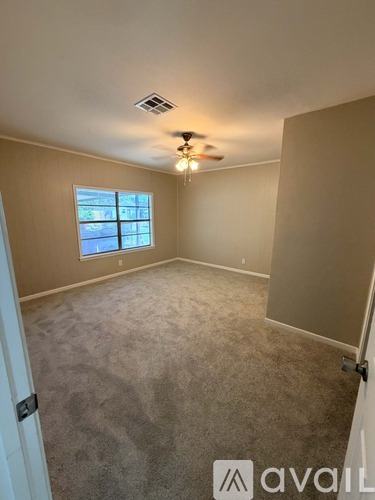 A room with a carpeted floor, a ceiling fan, and a window.
