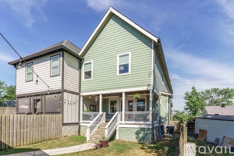 A two-story house with a green exterior and a wooden fence in front.