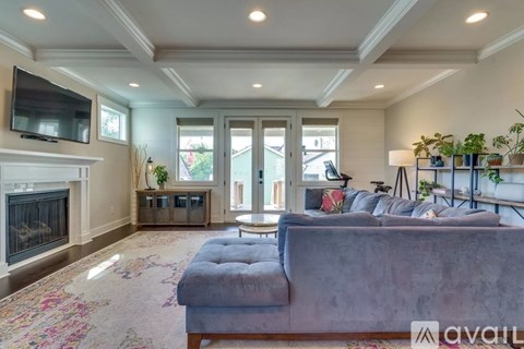 A living room with a grey couch and a fireplace.