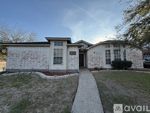 A house with a white door and a brick wall is shown.