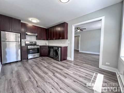 A kitchen with dark wood cabinets and a stainless steel refrigerator.