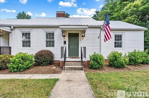 A white house with a green door and an American flag on the front.