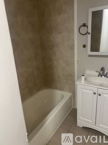 A bathroom with a tub, sink, and mirror.