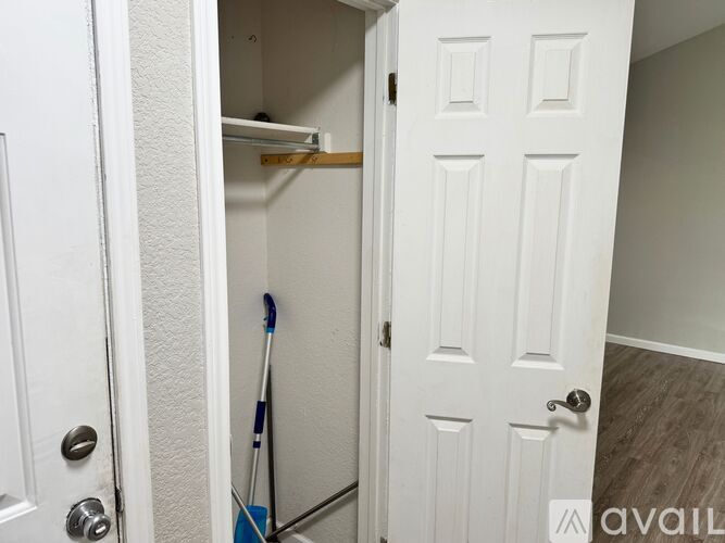 A white door with a handle and a broom leaning against the wall.