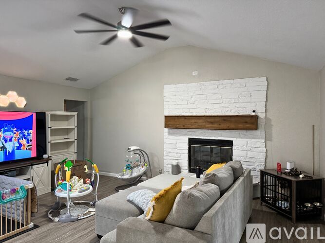 A living room with a grey couch, a white fireplace, and a television.