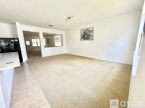 A spacious living room with a beige carpet and a framed picture on the wall.