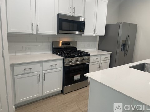 A kitchen with white cabinets and a stainless steel refrigerator.
