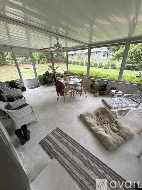 A sunroom with a white ceiling fan and a striped rug on the floor.