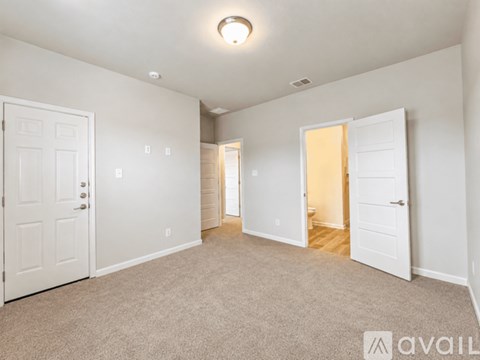 A spacious room with white doors and carpeted floor.