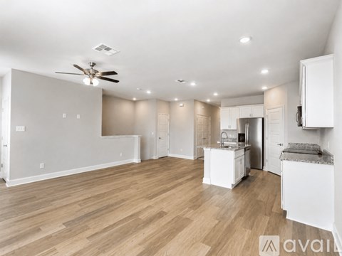 A spacious kitchen with white cabinets and a wooden floor.