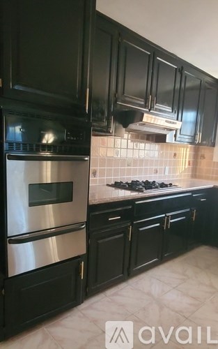 A kitchen with black cabinets and a stainless steel refrigerator.