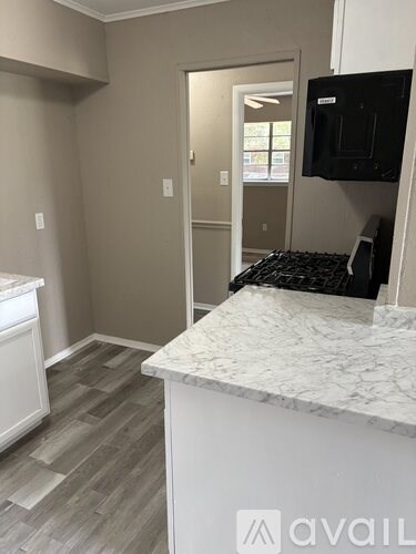 A kitchen with a white counter top and a black fridge.