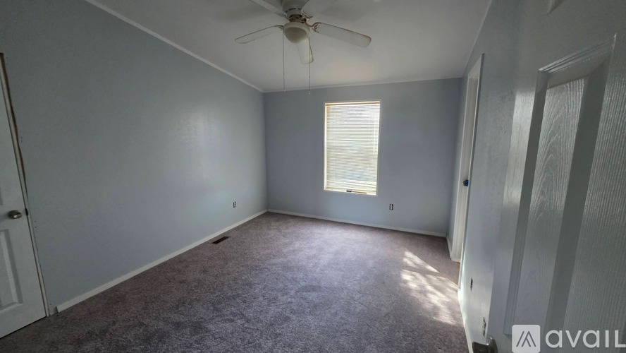 A room with a ceiling fan and a window with blinds.