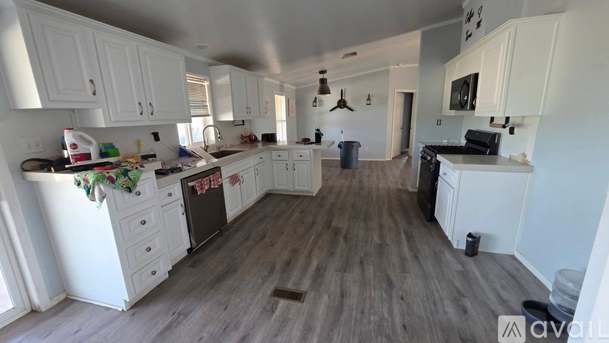 A kitchen with white cabinets and a wooden floor.