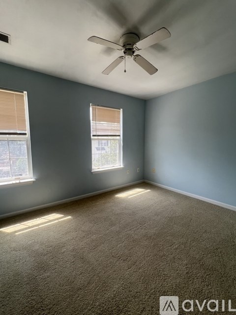 A room with a ceiling fan and two windows.