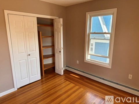 A room with a white door and a window with a view of a building outside.
