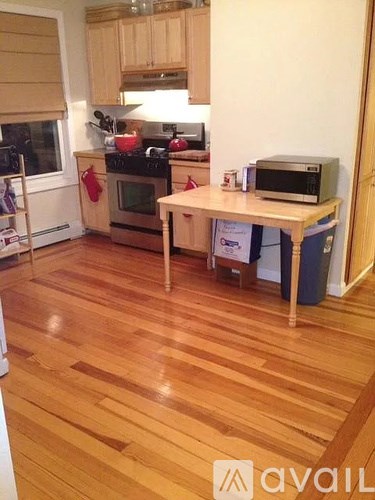 A kitchen with wooden floors and a table with a microwave on it.