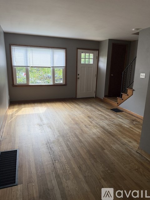 A room with wooden flooring and a window with blinds.