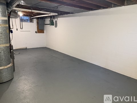 A spacious basement with a concrete floor and white walls.