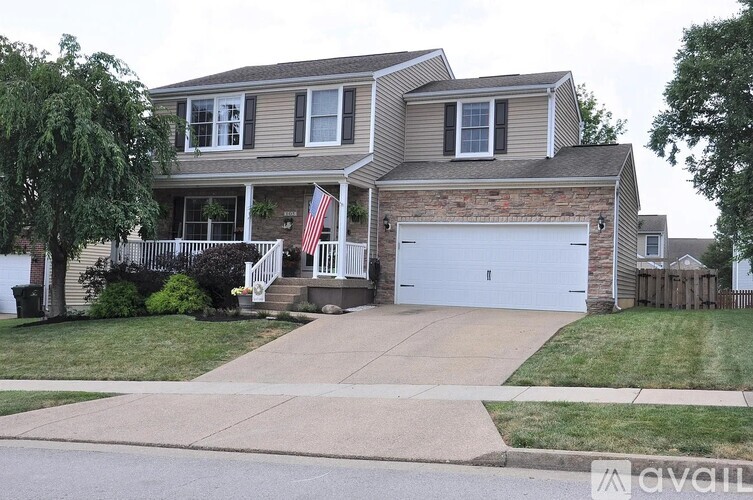 A two-story house with a garage and a flag on the front porch.