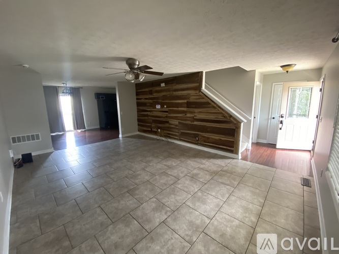A spacious room with a tiled floor and a staircase with wooden steps.