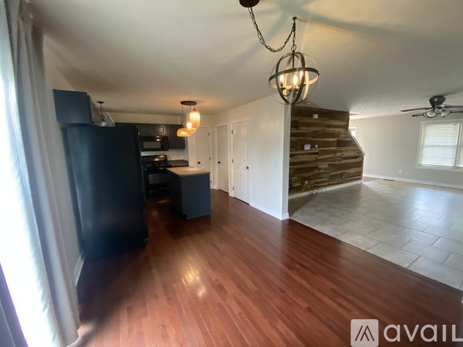 A kitchen with dark wood floors and a chandelier hanging from the ceiling.
