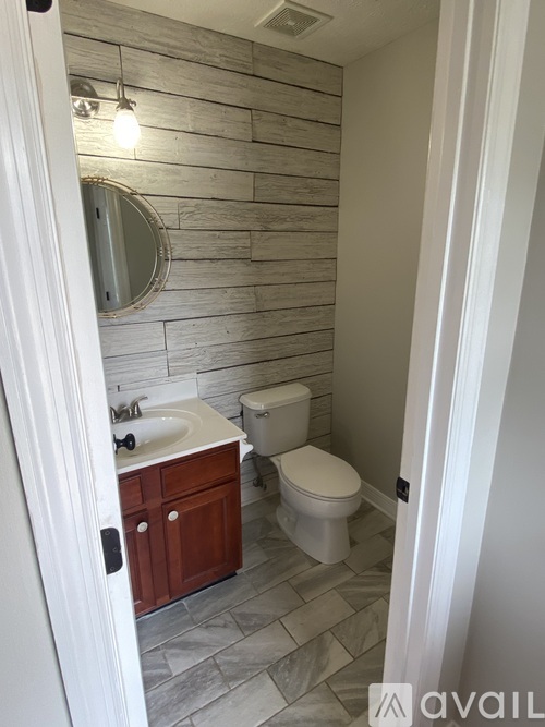 A bathroom with a toilet, sink, and mirror.