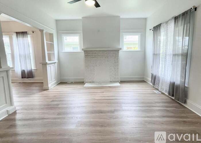 A spacious room with wooden floors and a fireplace.