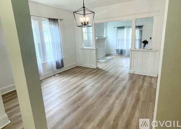 A room with wooden floors and a chandelier hanging from the ceiling.