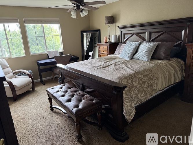 A bedroom with a large bed, a chair, and a window.