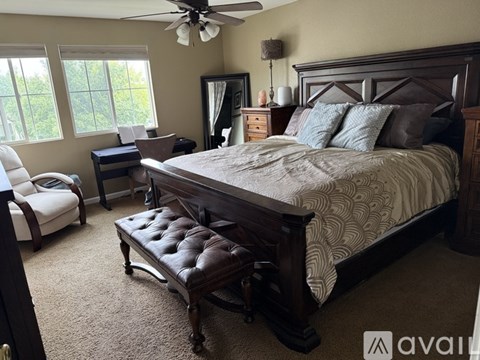 A bedroom with a large bed, a chair, and a window.