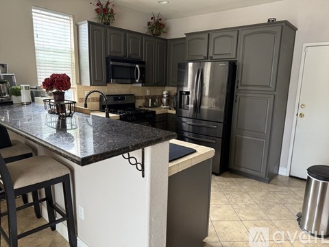 A kitchen with a black granite countertop and a black fridge.