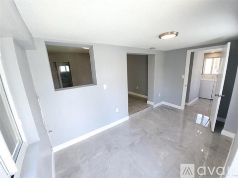 A spacious room with a window and a door leading to another room.
